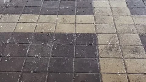 Close-up of raindrops and hail hitting the paving slabs. Video footage of Stockbeeldmateriaal 334017165