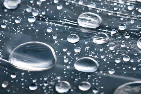 Close-up of raindrops of different sizes on the surface covered with cling film Stock Photos
