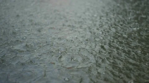 Close-up of raindrops falling into a puddle on the pavement. Heavy torrential Stock Footage 204948234