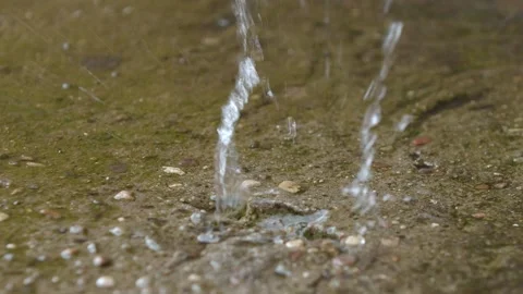 Close-up of raindrops falling on a stone surface and creating splashes Stock Footage 131652980