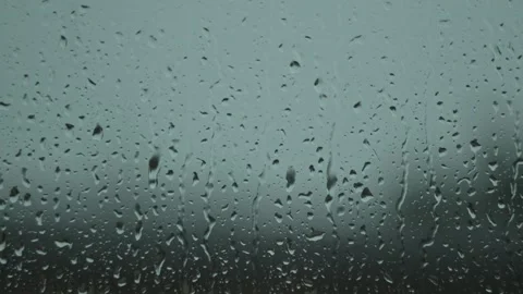 Close-up of raindrops falling on a window surface with a blurred background. Stock Footage 295210679