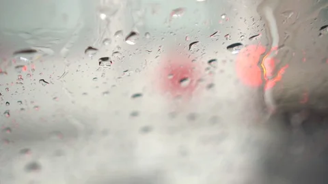 Close up of raindrops flowing down on windshield. Red lights of car in front Stock Footage 80267552