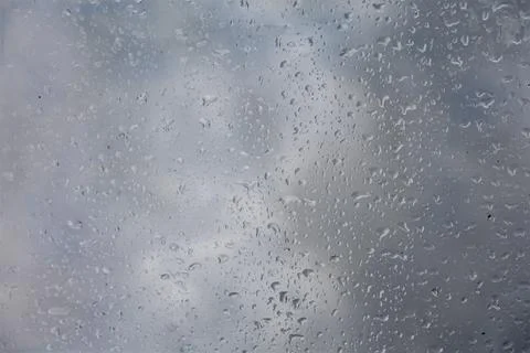 Close-up of raindrops on a window pane with a cloudy sky background Stock Photos
