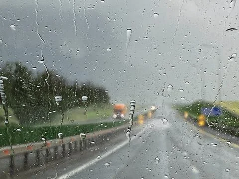 Close-up of raindrops from the windshield, dark cloud, heavy rain, the road is Stock-Fotos