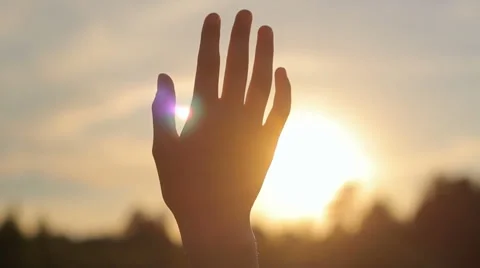 Close-up of raised hand in the sky against the sun in nature, peace, hope Stock Footage