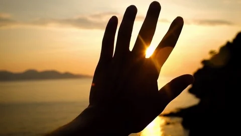 Close-up of raised hand in the sky against the sunset over sea. Vídeos de archivo 73128498