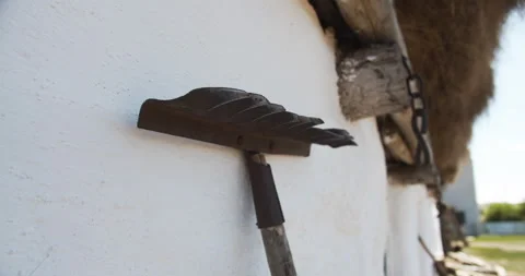 Close up. Rake stands against the white wall of a village house with a reed roof Stock Footage 141782682
