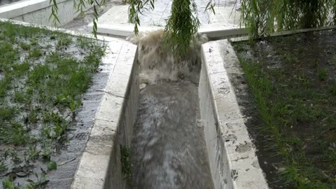 Close-up, a rapid stream of dirty water flows into the river through a stone  스톡 동영상 141930868