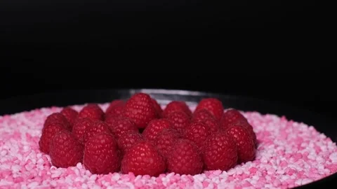 Close-up of raspberries and raspberry flavoured candy pieces rotating on a plate Stock Footage 240098162