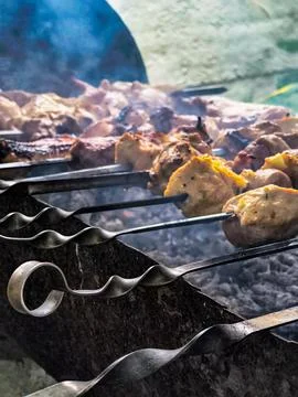 Close-up of raw and partially cooked marinated meat on metal skewers roasting Stock Photos