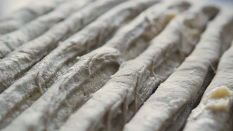 Close-up of raw bread dough sticks arranged in rows, dusted with flour.  Stock Footage 331851776