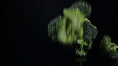Close-up of raw broccoli is falling down on black background Stock Footage 102616882
