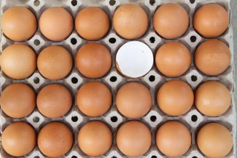 Close up of raw brown eggs in an egg carton, one egg  is broken Stock Photos