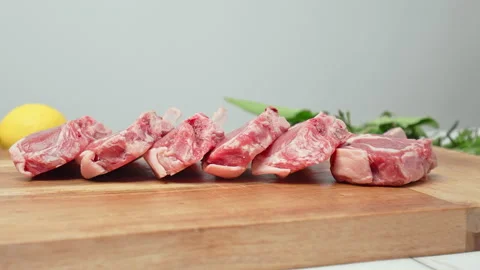 Close-up raw chopped lamb ribs on cutting board with decorative vegetables in 4K Stock Footage 145995996