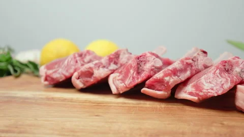 Close-up raw chopped lamb ribs on cutting board with decorative vegetables in 4K Stock Footage 145996206