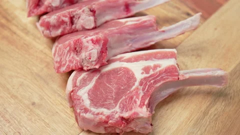 Close-up raw chopped lamb ribs on cutting board with decorative vegetables in 4K Stock Footage 145996616