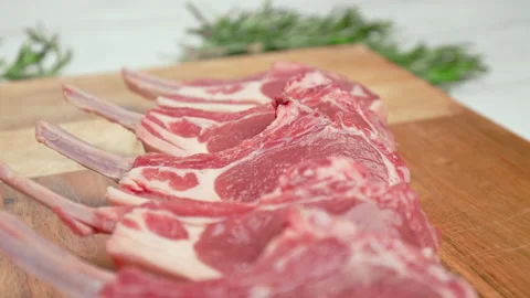 Close-up raw chopped lamb ribs on cutting board with decorative vegetables in 4K Stock Footage 145996930