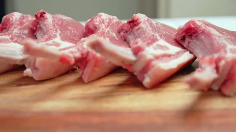 Close-up raw chopped lamb ribs on cutting board with decorative vegetables in 4K Stock Footage 145996990