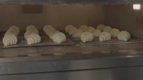 Close-up of raw croissants on trays inside a commercial oven Stockbeeldmateriaal 327353231