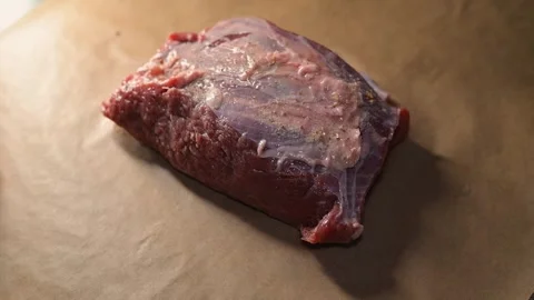 A close-up of raw meat resting on a kitchen surface as plastic packaging is Stock Footage 339097467