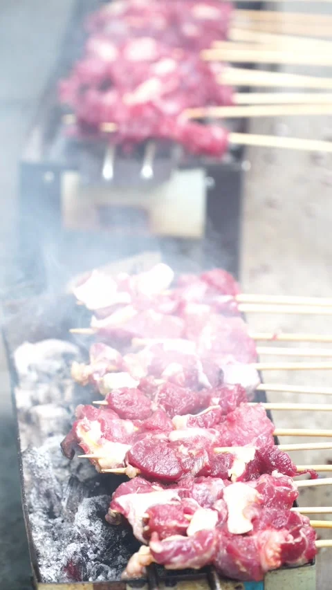 Close-up of Raw Mutton Satay Grilling on Charcoal Grill with Smoke Stock Footage 346333295