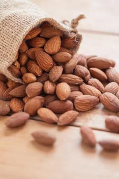 Close up raw peeled almonds seed in sack on wooden background.. Stock Photos