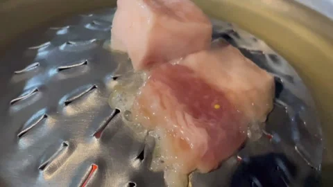 Close-up of raw pork being steamed in a metal container. Video stock 326439065