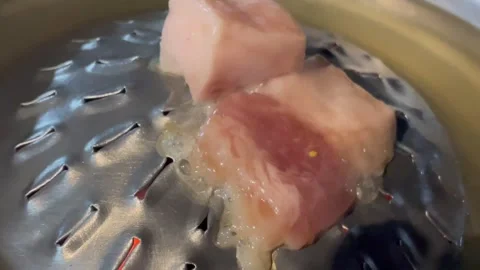 Close-up of raw pork being steamed in a metal container. Video stock 326439070