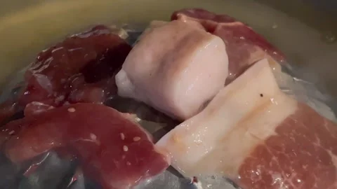 Close-up of raw pork being steamed in a metal container. Stock Footage 326439072