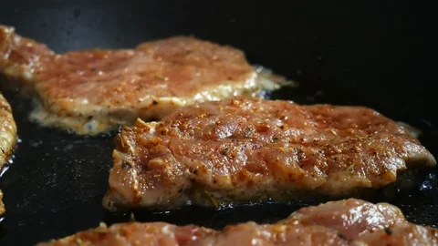 Close-up of raw pork chops are fried in a frying pan Stock Footage 102769430