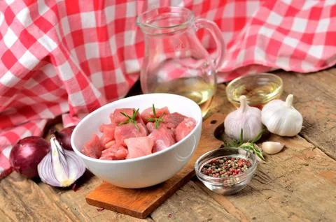 Close-up of raw pork meal diced in a bowl, garlic, half of onion, pepper, jug Stock Photos