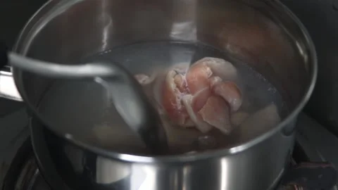 Close up of raw pork in stainless pot containing boiling water being stir chef Video stock 158935663