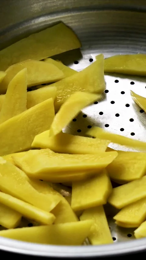 Close-up of Raw Potato Wedges Falling into Metal Pot Stockbeeldmateriaal 330896980