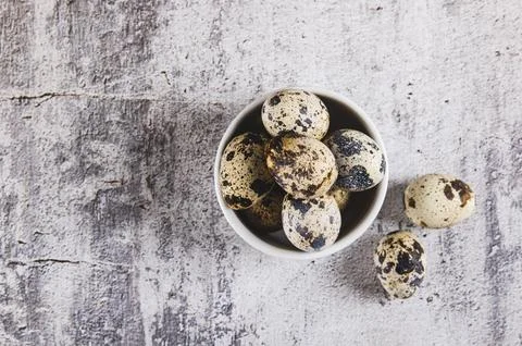 Close up of raw quail eggs in their shells in a bowl on the table top view Stock Photos