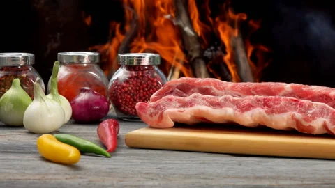 Close-up of the raw ribs laying next to ingredients on the background of fire Stock Footage 169786674