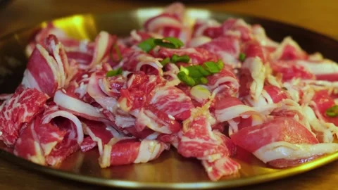 Close-up of raw sliced beef with marbled fat served on golden plate, garnished Stock Footage 306951147