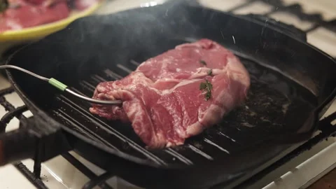 Close-up of raw steak being grilled in a cast iron pan with herbs Stock Footage 340563282