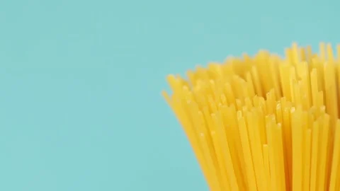 Close up of raw unprepared spaghetti rotating on blue background Stock Footage 202632847