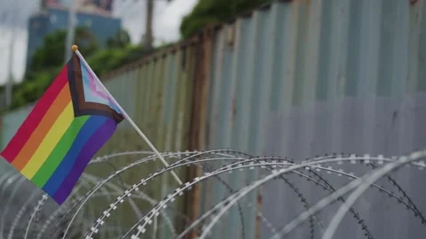 Close-up of razor barbed wire barricade in front of containers with pride flag. Vídeos de archivo 158135382