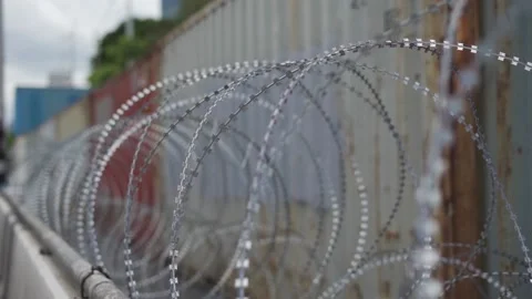 Close-up of razor barbed wire barricade in front of shipping containers. Stock Footage 158135390