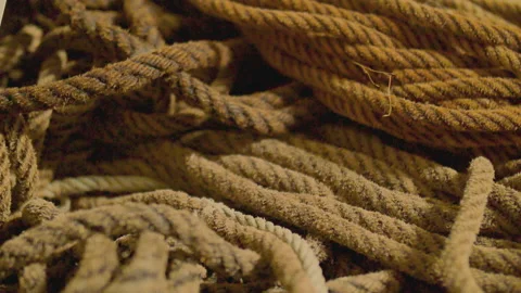 Close up of really long rolled up brown worn out rope laying on ground Stock Footage 157213688