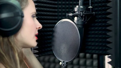 Close-up rear side view of a young talented singer in headphones singing into a  Stock-Footage 119259847