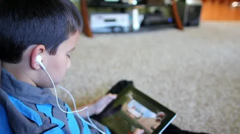 Close up rear view of boy playing game on tablet wearing headphones Stock Footage
