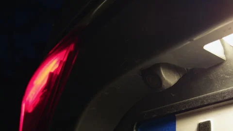 Close-up rear view camera beside glowing tail light on parked car at night Stock Footage 338134707