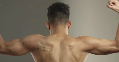 Close-up rear view of dark-skinned sportsman back, athlete flex biceps on arms Stock Footage 137409684