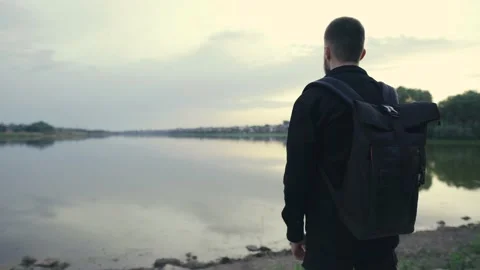 Close-up rear view of a man with a backpack walking near a lake, landscape 스톡 동영상 133367163