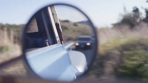 Close-up of the rear view mirror of an old pickup truck as it drives through a Vidéo 34484757
