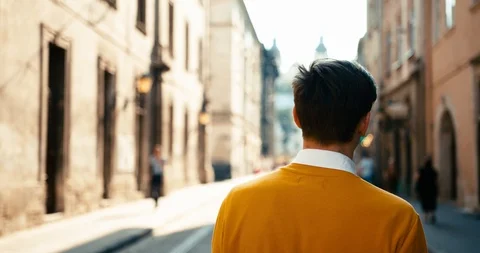 Close-up rear view of the unknown man in yellow sweater walking along the Stock Footage 92007311