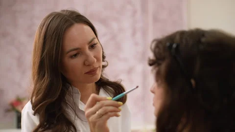 Close-up rear view of working professional makeup artist applying eyeshadow to Stock Footage 244935504
