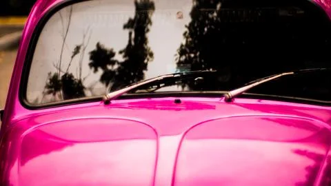 Close up of rear windshield wiper arm and blade on sun bleached pink vintag.. Stock Photos